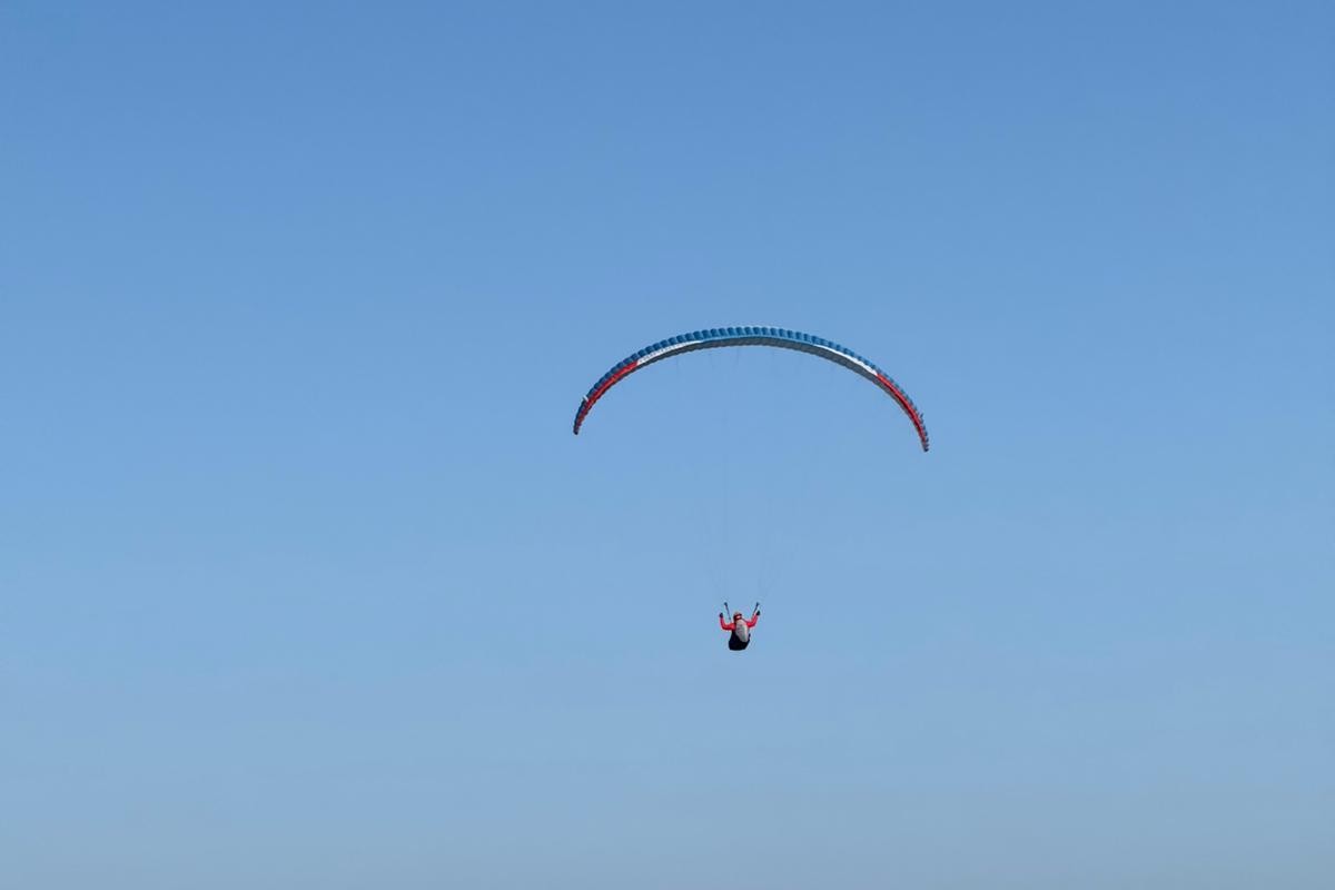 A paraglider flying over mountains and a lake